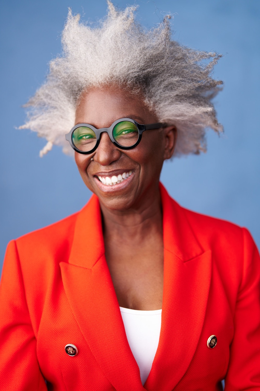 Andrea smiling in a red blazer against a blue background