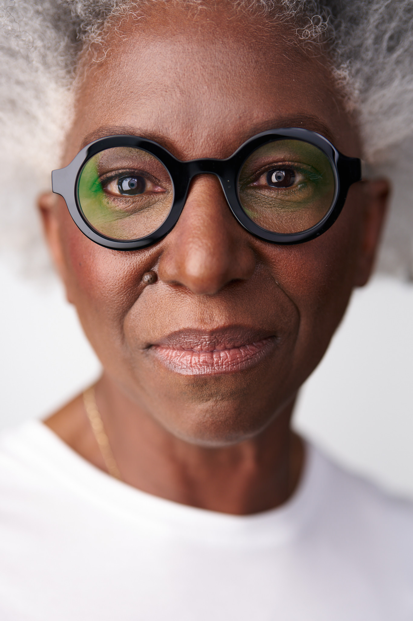 Close portrait of Andrea in a white top against a white background